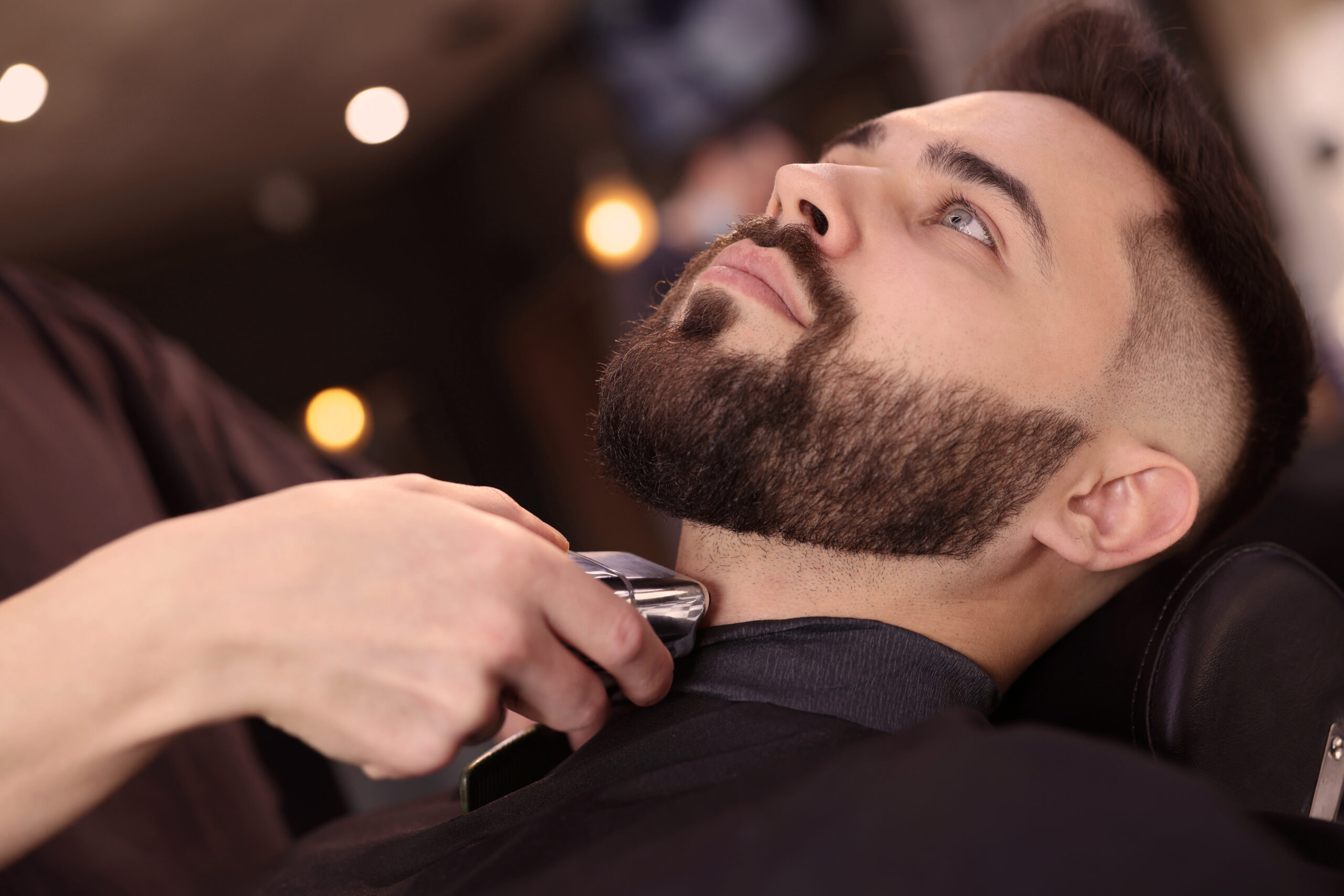 Professional hairdresser working with client in barbershop